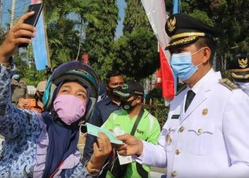 Bupati Barito Utara saat diajak berselfie bersama masyarakat pengguna jalan setelah memberikan masker