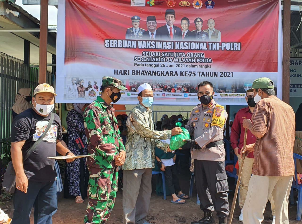 Kapolsek Kapuas Timur Iptu Eko Sutrisno menyerahkan sembako saat kegiatan vaksinasi di UPT Puskesmas Kapuas Timur