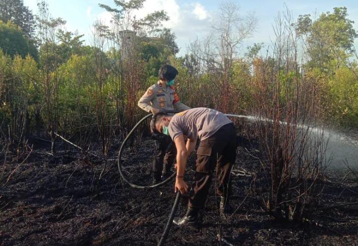 Personel kepolisian saat melakukan pemadaman di lahan yang terbakar