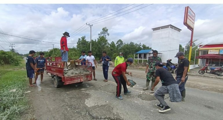 Mahasiswa KKNTM 2021 bersama warga dan aparat desa saat bergotong royong menambal jalan yang berlubang di desa Sababilah, Jumat (26/11/2021)