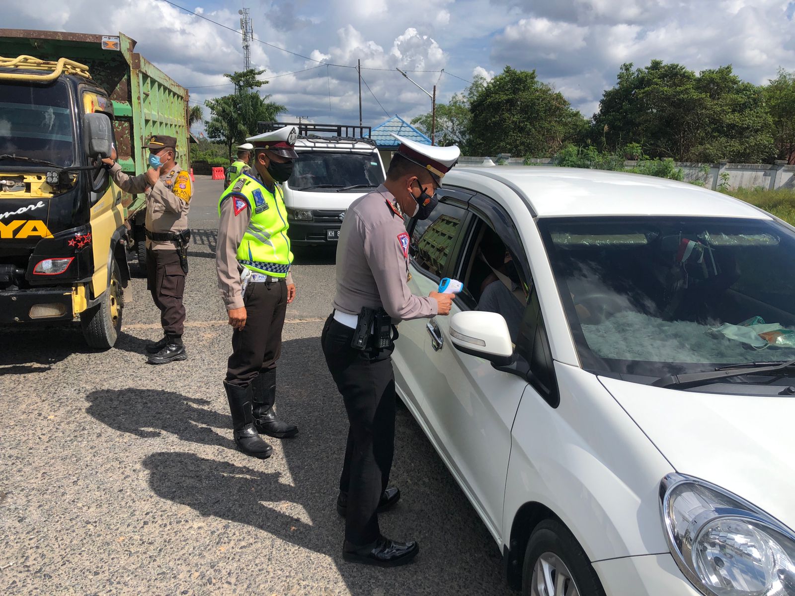 Kasat Lantas saat melakukan pemeriksaan suhu kepada pengemudi mobil