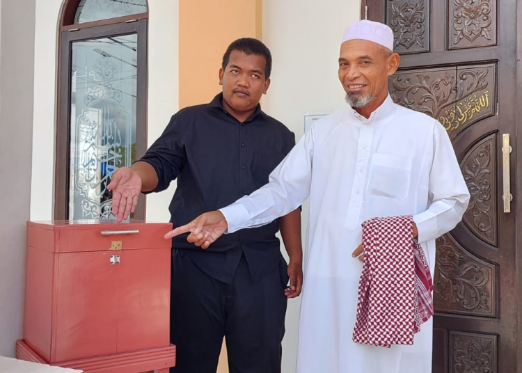 Pengurus Masjid Nurul Ikhwan, Mahfud bersama warga menunjukkan kotak amal bekas dibobol pelaku.