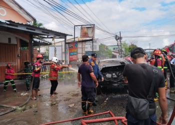 Petugas pemadam saat melakukan upaya pemadaman mobil terbakar